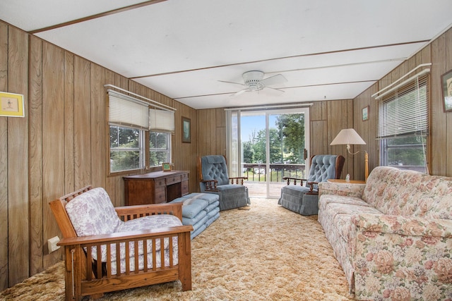 living room with a wealth of natural light, wooden walls, and ceiling fan