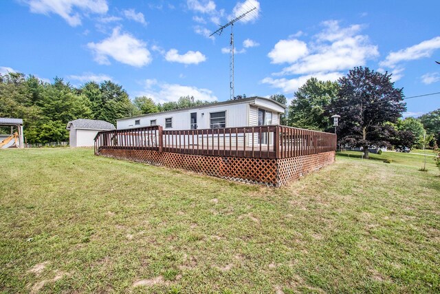 6662 Lorne Dr, Pentwater, MI 49449 - back of property featuring a deck, a lawn, an outdoor structure, and a detached garage