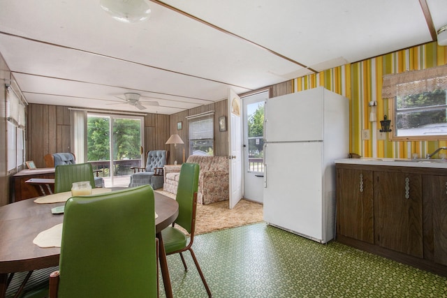 dining room featuring ceiling fan, wooden walls, and sink