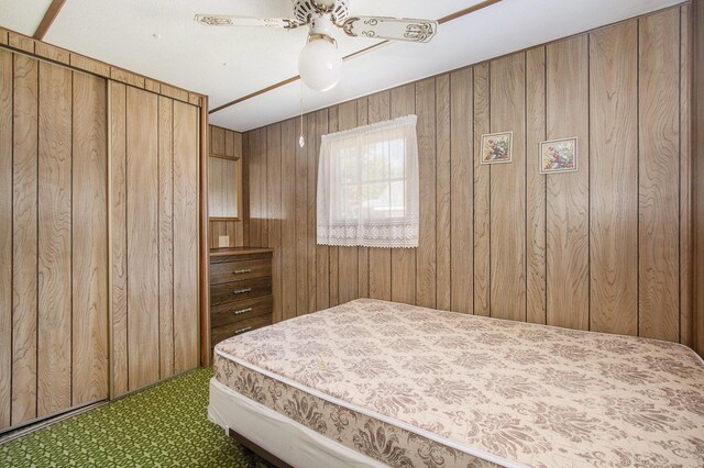 6662 Lorne Dr, Pentwater, MI 49449 - bedroom featuring carpet flooring, wooden walls, and a ceiling fan