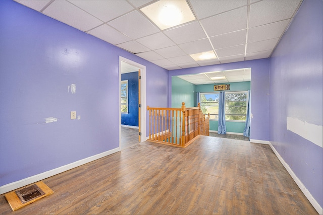 empty room with hardwood / wood-style flooring and a drop ceiling