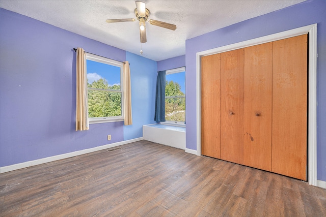 unfurnished bedroom with dark hardwood / wood-style floors, ceiling fan, a textured ceiling, and a closet