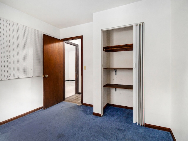 unfurnished bedroom featuring dark colored carpet and a closet