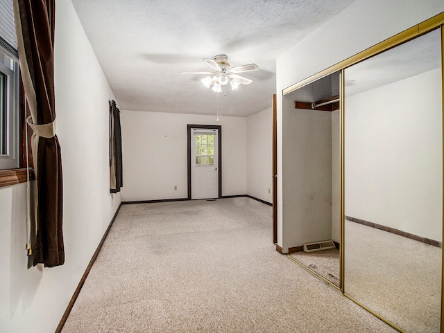 carpeted spare room featuring ceiling fan and a textured ceiling