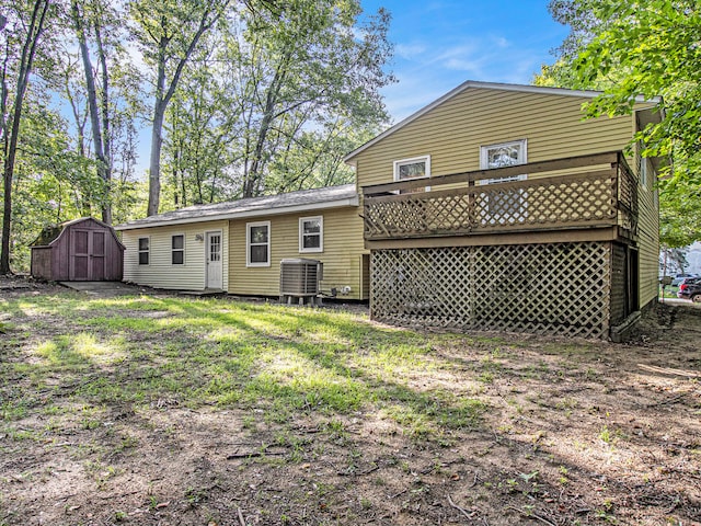 rear view of house featuring a lawn, a shed, and central AC