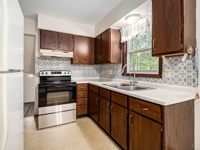 kitchen featuring dark brown cabinetry, electric range, sink, backsplash, and white fridge