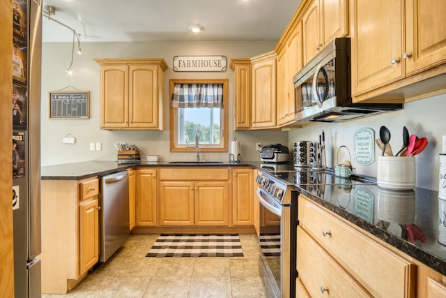 kitchen featuring light brown cabinets, sink, dark stone countertops, light tile patterned floors, and stainless steel appliances