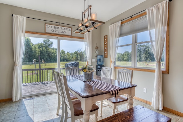 dining space featuring light tile patterned floors, a healthy amount of sunlight, and an inviting chandelier