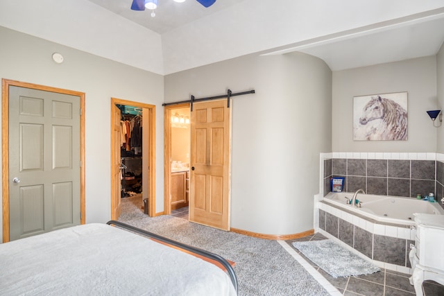 bedroom featuring a barn door, a closet, a spacious closet, and ceiling fan