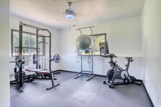 exercise area with ceiling fan and a textured ceiling