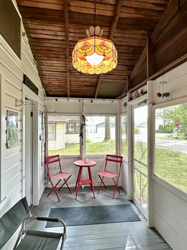 unfurnished sunroom featuring vaulted ceiling, a healthy amount of sunlight, and wood ceiling