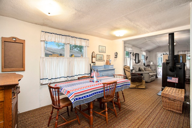 carpeted dining area with lofted ceiling, a textured ceiling, and a wood stove