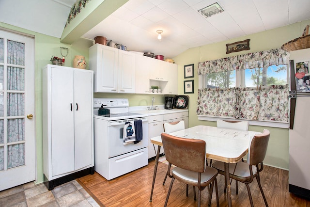 kitchen with white cabinetry, light hardwood / wood-style floors, lofted ceiling, and white electric range