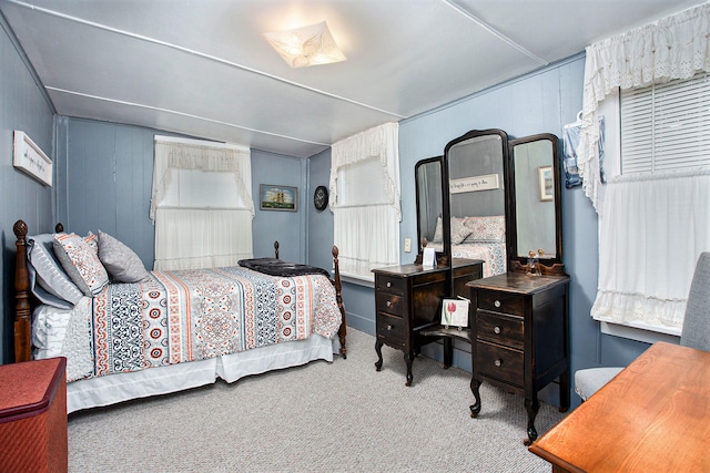 bedroom with light colored carpet and wood walls