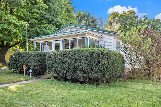 view of front of home with a sunroom and a front lawn