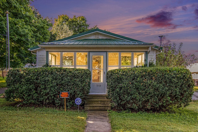 bungalow-style house with a sunroom and a yard