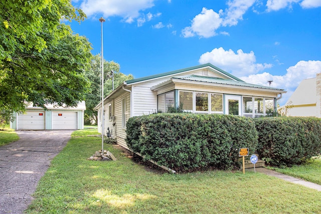 view of front of home with a garage, an outbuilding, and a front lawn