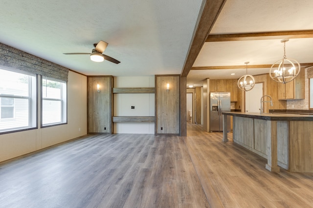 kitchen with ceiling fan with notable chandelier, wood-type flooring, beamed ceiling, stainless steel fridge with ice dispenser, and hanging light fixtures