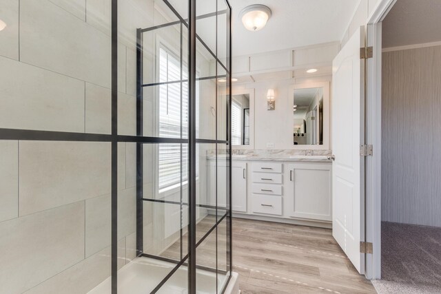 645 N Gallery Dr Unit 98, Eaton Rapids, MI 48827 - bathroom featuring double vanity, a shower stall, and wood finished floors