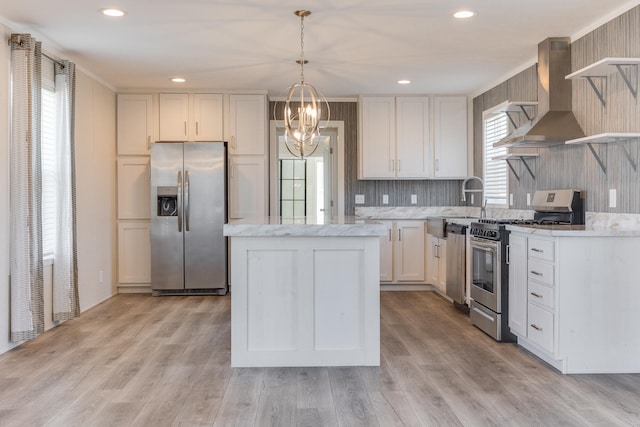 kitchen with ventilation hood, hanging light fixtures, light hardwood / wood-style flooring, white cabinetry, and stainless steel appliances