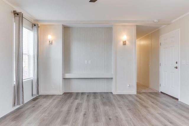 unfurnished living room featuring plenty of natural light, crown molding, and light hardwood / wood-style flooring