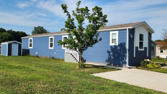 view of side of home with a lawn, a patio, and a shed