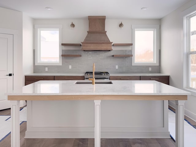 kitchen featuring a breakfast bar, custom exhaust hood, and an island with sink