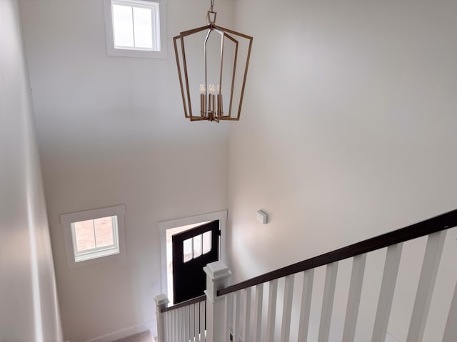 stairway with healthy amount of natural light, a chandelier, and a towering ceiling