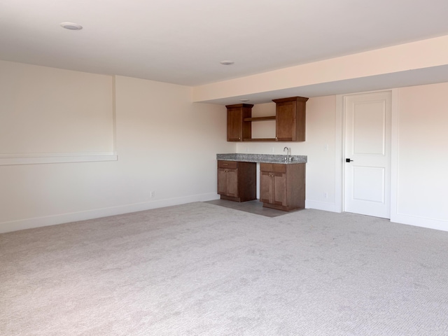 kitchen featuring baseboards and light colored carpet