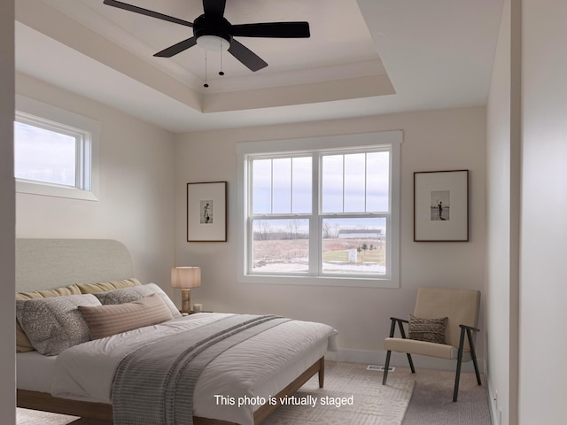 bedroom featuring a raised ceiling, carpet, baseboards, and a ceiling fan