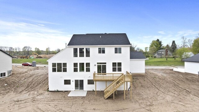 back of house with stairs, a deck, and roof with shingles