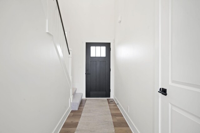 doorway with stairway, baseboards, and wood finished floors