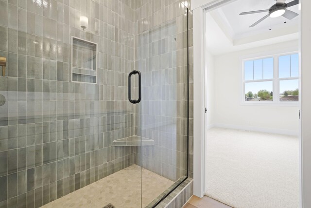 full bathroom featuring a stall shower, ceiling fan, a tray ceiling, and baseboards