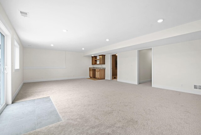 basement featuring wet bar, light colored carpet, recessed lighting, and baseboards