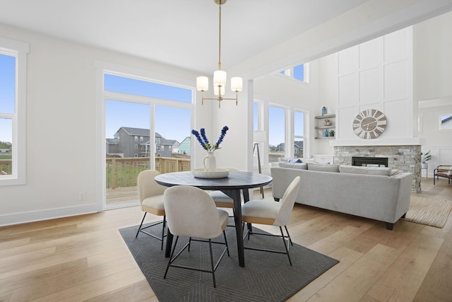 dining area with plenty of natural light, light wood finished floors, a fireplace, and a high ceiling
