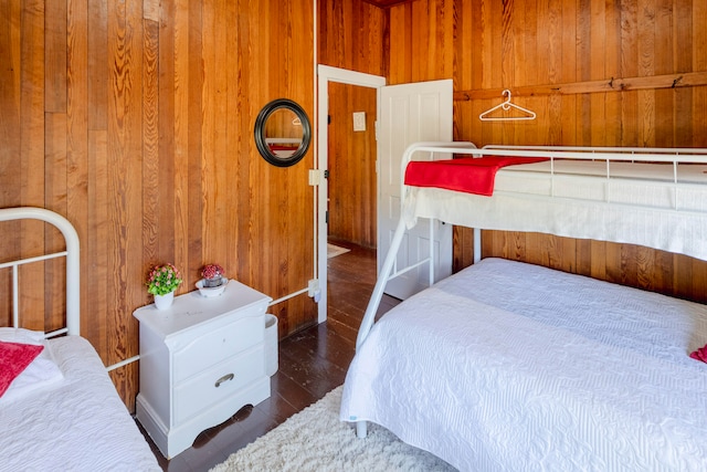 bedroom with wooden walls and dark hardwood / wood-style flooring