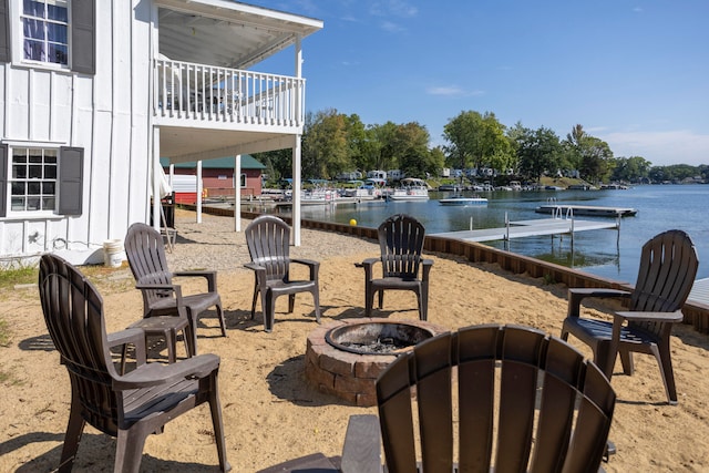 view of patio featuring a dock, a water view, a fire pit, and a balcony