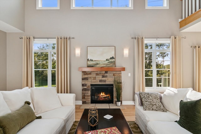 living area featuring plenty of natural light, a high ceiling, and a stone fireplace