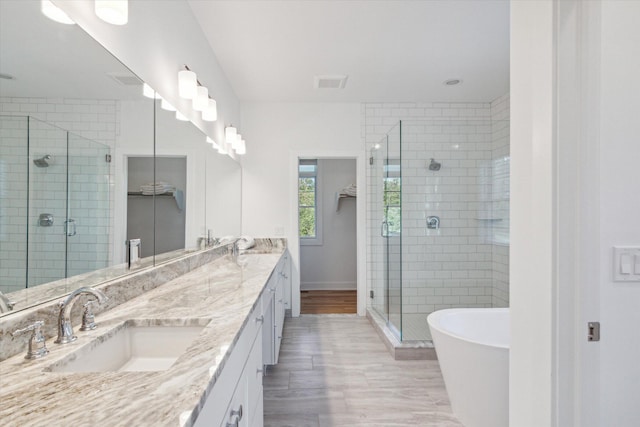 bathroom featuring double vanity, a stall shower, a sink, and visible vents