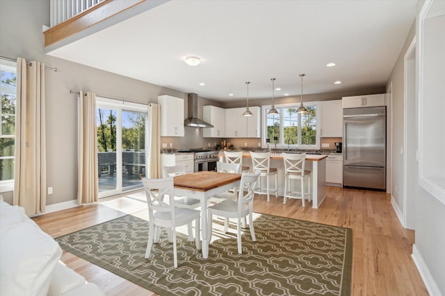 dining area with light wood-type flooring, a healthy amount of sunlight, baseboards, and recessed lighting