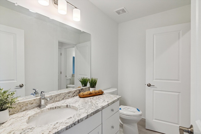 bathroom with visible vents, vanity, and toilet