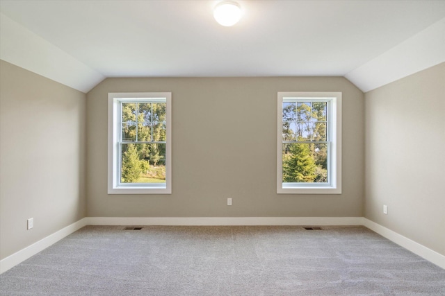 additional living space featuring lofted ceiling, visible vents, and a healthy amount of sunlight