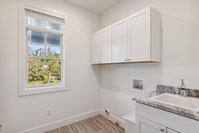 washroom with hookup for a washing machine, cabinet space, light wood-style floors, a sink, and baseboards