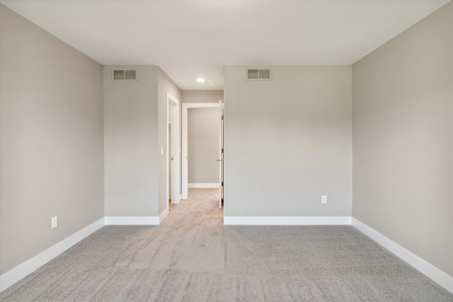 spare room with carpet floors, visible vents, and baseboards