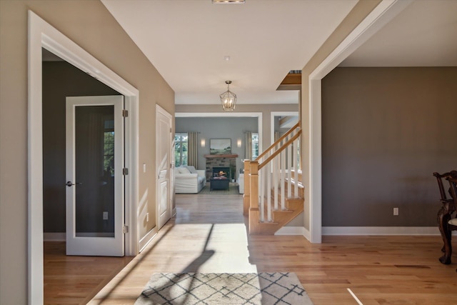 foyer featuring light wood-style floors, stairway, a lit fireplace, and baseboards