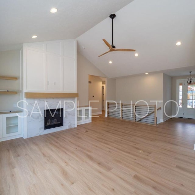 unfurnished living room with a fireplace, vaulted ceiling, light hardwood / wood-style flooring, and ceiling fan