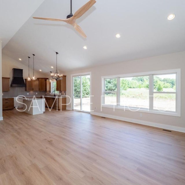 unfurnished living room featuring lofted ceiling, light wood-type flooring, and ceiling fan with notable chandelier