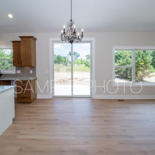 unfurnished dining area featuring light wood-type flooring and an inviting chandelier