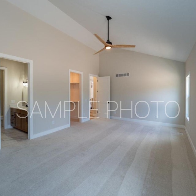 unfurnished bedroom with a walk in closet, light colored carpet, a closet, and ceiling fan