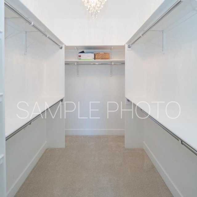 spacious closet with light carpet and an inviting chandelier